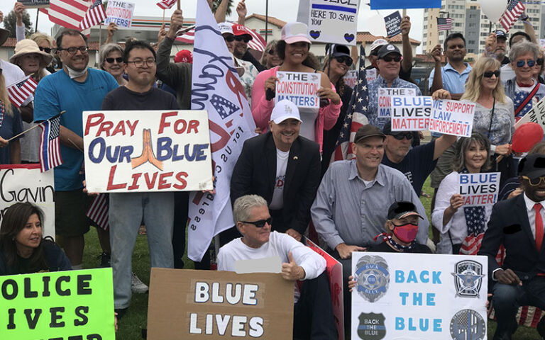 Enthusiastic rally supporters holding placards and smiling at a public demonstration